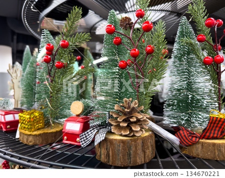 Whimsical small Christmas trees decorated with red berries, pinecones, and tiny red trucks, setting a festive holiday mood for winter celebrations Whimsical small Christmas trees decorated with red berries, pinecones, and tiny red trucks, setting a festive holiday mood for winter celebrations 134670221