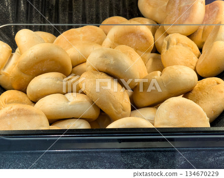 Freshly baked golden brown bread rolls are piled high in a bakery display, symbolizing abundance and delicious food for daily consumption Freshly baked golden brown bread rolls are piled high in a bakery display, symbolizing abundance and delicious food for daily consumption 134670229
