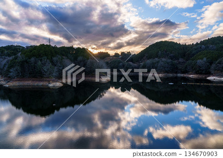 Nara Nunome Dam water shortage in December evening view. Clouds spreading in the sunset sky and reflected in Nunome Lake. 134670903