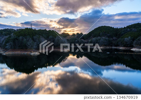 Nara Nunome Dam water shortage evening scene in December. Clouds spreading in the sunset sky and reflected in Nunome Lake. 134670919