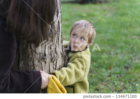 Happy Mother and Young Son Playing on Wooden Seesaw at Outdoor Playground Happy Mother and Young Son Playing on Wooden Seesaw at Outdoor Playground 134671100