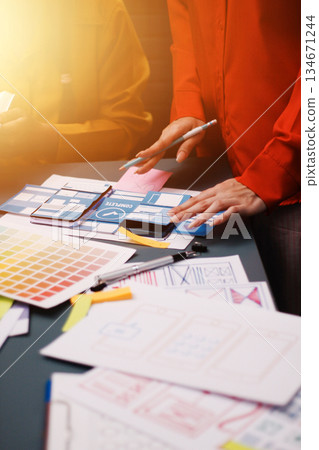Team of uxui designers pointing at computer screen, discussing new mobile app design in the office 134671244