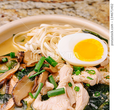 Tasty chicken noodle soup with egg and veggies at a restaurant 134671402