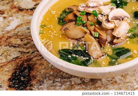Miso soup with mushrooms and seaweed served in a bowl on a marble countertop Miso soup with mushrooms and seaweed served in a bowl on a marble countertop 134671415