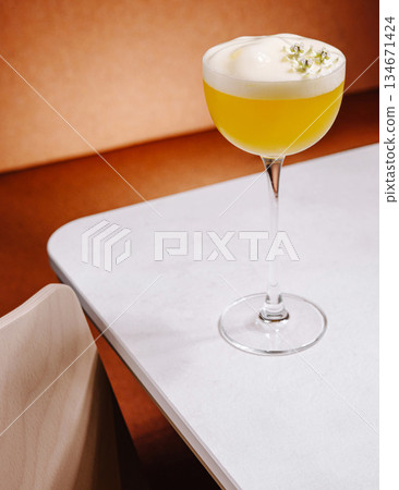 Bright yellow cocktail served in an elegant glass on a minimalistic table Bright yellow cocktail served in an elegant glass on a minimalistic table 134671424