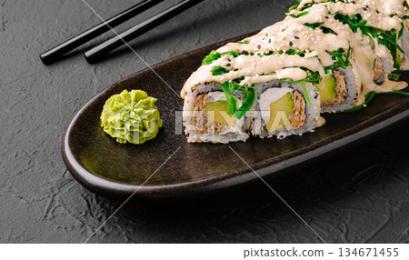 Sushi roll served on a dark plate with wasabi and pickled ginger 134671455