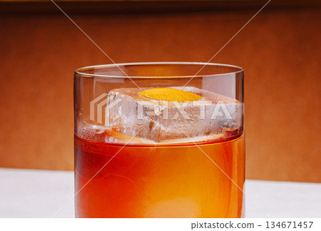 Craft cocktail served in a clear glass with ice and orange garnish at a bar Craft cocktail served in a clear glass with ice and orange garnish at a bar 134671457