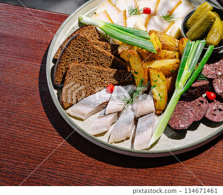 Assorted cured meats, fish, and sides served on a round plate 134671461