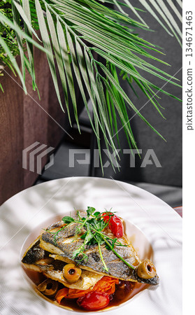 Deliciously plated fish dish with fresh herbs and tomatoes in a modern setting Deliciously plated fish dish with fresh herbs and tomatoes in a modern setting 134671463