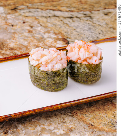 Sushi rolls with shrimp on a white plate atop a granite surface Sushi rolls with shrimp on a white plate atop a granite surface 134671496