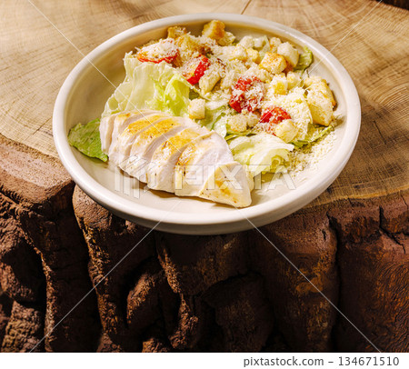 Fresh salad with grilled chicken served on a rustic wooden table Fresh salad with grilled chicken served on a rustic wooden table 134671510