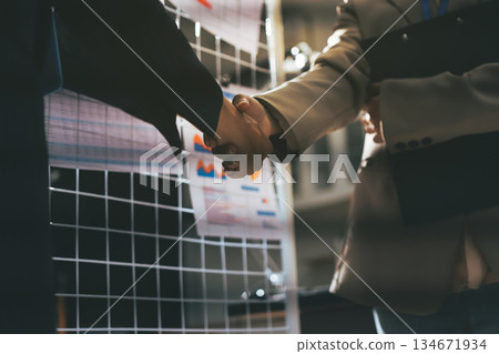Business people shaking hands in office. Two business partners shaking hands after signing a contract in office. 134671934