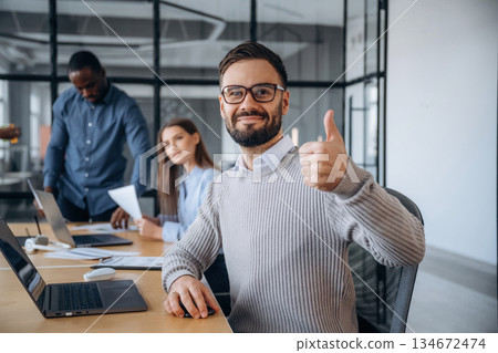 According to plan, showing thumb up. Professional workers are in the modern office together According to plan, showing thumb up. Professional workers are in the modern office together 134672474