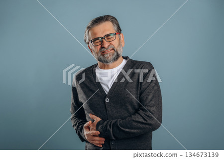 Pain in the right side. Senior man is standing in the studio against background 134673139