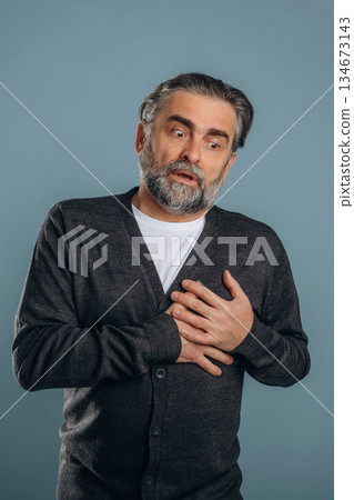 Pain in the chest, heart attack. Senior man is standing in the studio against background Pain in the chest, heart attack. Senior man is standing in the studio against background 134673143