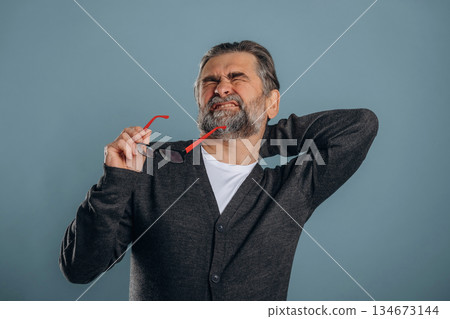Neck pain. Senior man is standing in the studio against background 134673144