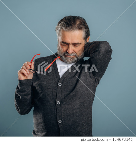 Neck pain. Senior man is standing in the studio against background 134673145