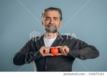 Take care of your heart, healthcare concept. Senior man is standing in the studio against background Take care of your heart, healthcare concept. Senior man is standing in the studio against background 134673161