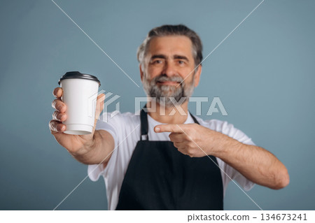 The waiter is with fresh coffee. Senior man is standing in the studio against background The waiter is with fresh coffee. Senior man is standing in the studio against background 134673241