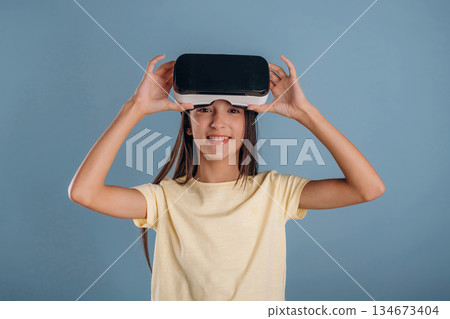 With virtual reality headset. Young girl is against background With virtual reality headset. Young girl is against background 134673404