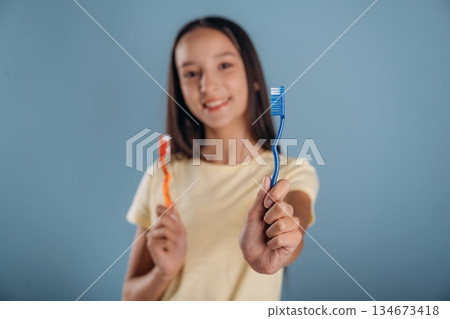 Conception of personal hygiene, with toothbrush. Young girl is against background Conception of personal hygiene, with toothbrush. Young girl is against background 134673418