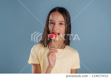 Red sweet candy. Young girl is against background Red sweet candy. Young girl is against background 134673432