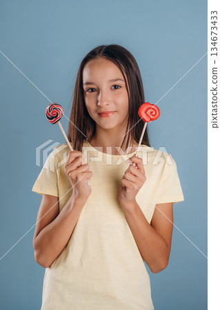 Sweet candies. Young girl is against background Sweet candies. Young girl is against background 134673433