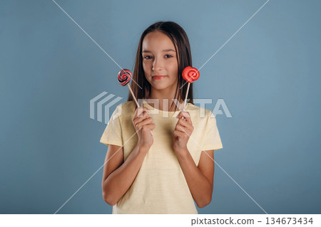 Sweet candies. Young girl is against background Sweet candies. Young girl is against background 134673434