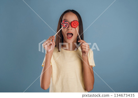 Sweet candies. Young girl is against background Sweet candies. Young girl is against background 134673435