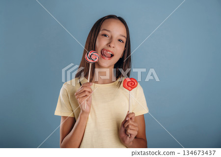 Sweet candies. Young girl is against background Sweet candies. Young girl is against background 134673437