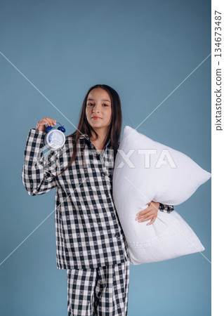 Sleep time, with clock. Young girl in pajama is against background Sleep time, with clock. Young girl in pajama is against background 134673487