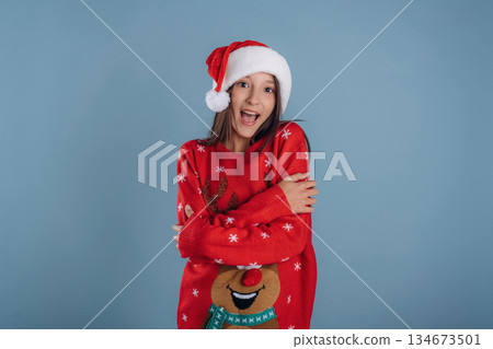 In Christmas clothes. Young girl is against background In Christmas clothes. Young girl is against background 134673501