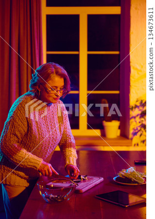 Senior woman cooking while interacting with virtual assistant interface Senior woman cooking while interacting with virtual assistant interface 134673611