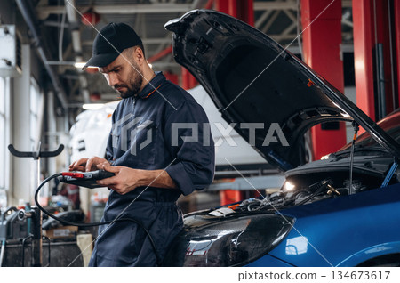 Electronics adjustment, with digital tablet. Mechanic working in a car service station 134673617
