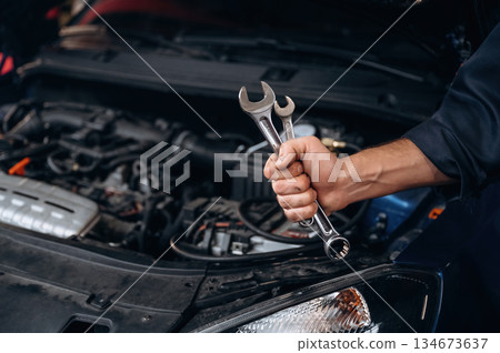 Tools in hand. Close up view of mechanic in car service station Tools in hand. Close up view of mechanic in car service station 134673637