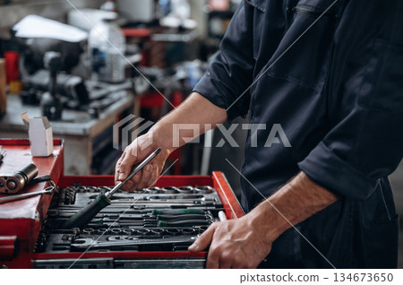 Table with many of tools. Close up view of mechanic in car service station 134673650
