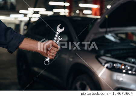 Showing tools, holding in hands. Close up view of mechanic in car service station 134673664