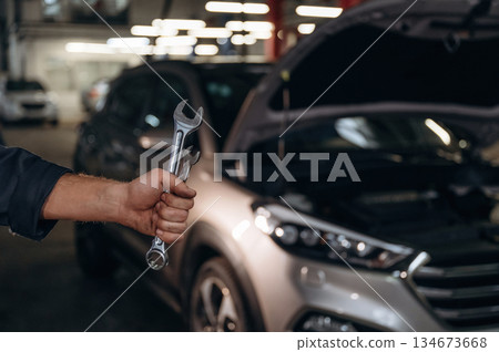 Showing tools, holding in hands. Close up view of mechanic in car service station 134673668