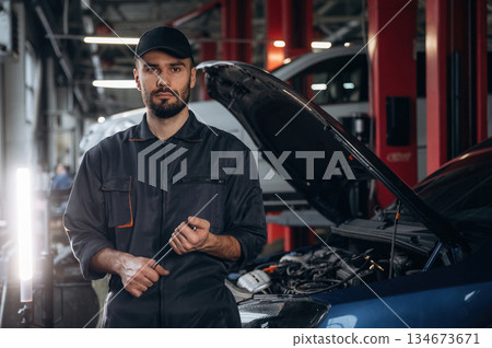 Front view, standing and holding tool. Mechanic working in a car service station 134673671