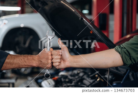 Hands of mechanic and client, holding tool, car service station Hands of mechanic and client, holding tool, car service station 134673703