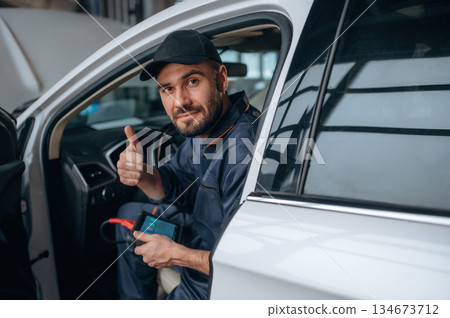 Sitting in automobile. Mechanic working in a car service station Sitting in automobile. Mechanic working in a car service station 134673712