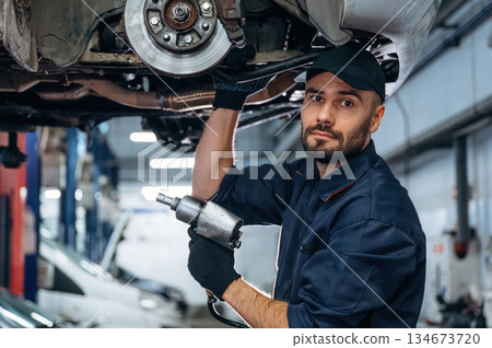 Automobile is up, hanging. Mechanic working in a car service station 134673720