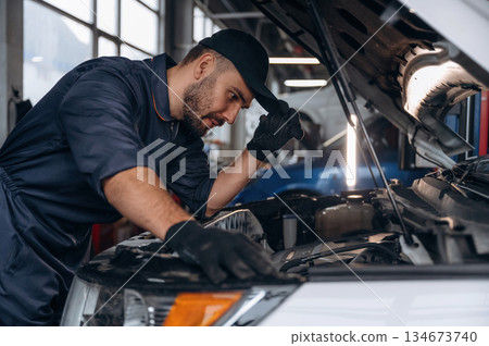 Busy, work is in progress. Mechanic is in a car service station Busy, work is in progress. Mechanic is in a car service station 134673740