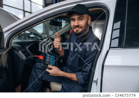 Thumb up, everything will be done. Mechanic working in a car service station 134673774
