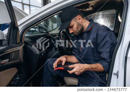 On the seat, with digital tablet. Mechanic working in a car service station On the seat, with digital tablet. Mechanic working in a car service station 134673777