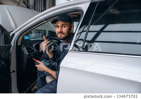 Sitting in automobile. Mechanic working in a car service station Sitting in automobile. Mechanic working in a car service station 134673781