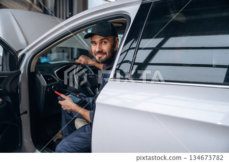 Sitting in automobile. Mechanic working in a car service station Sitting in automobile. Mechanic working in a car service station 134673782
