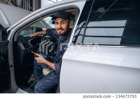Break time, sitting in automobile. Mechanic working in a car service station 134673783