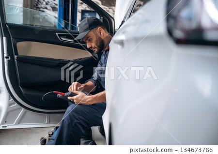 Break time, sitting in automobile. Mechanic working in a car service station Break time, sitting in automobile. Mechanic working in a car service station 134673786