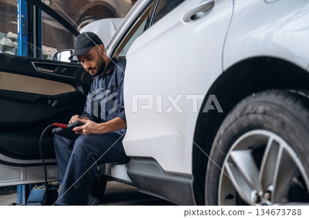 On the seat, with digital tablet. Mechanic working in a car service station On the seat, with digital tablet. Mechanic working in a car service station 134673788